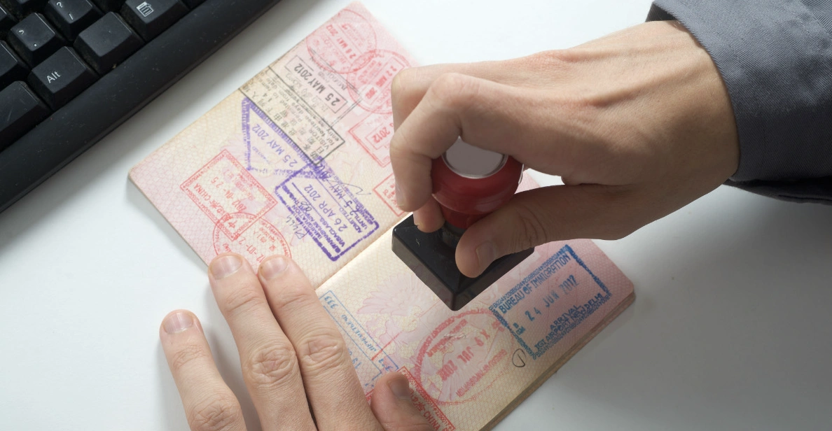 An immigration officer stamping a passport at an airport, symbolizing the final step of the entry process.